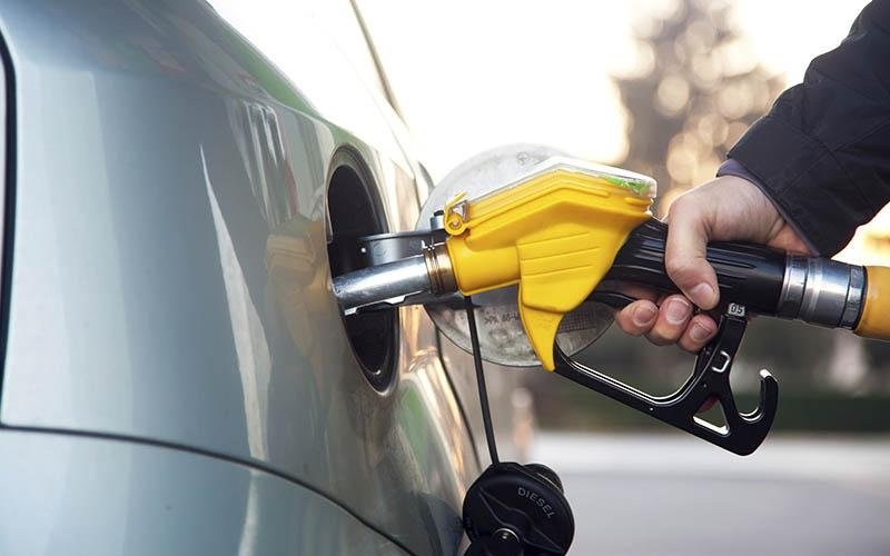 Persona che fa rifornimento a un'auto con pompa gialla.